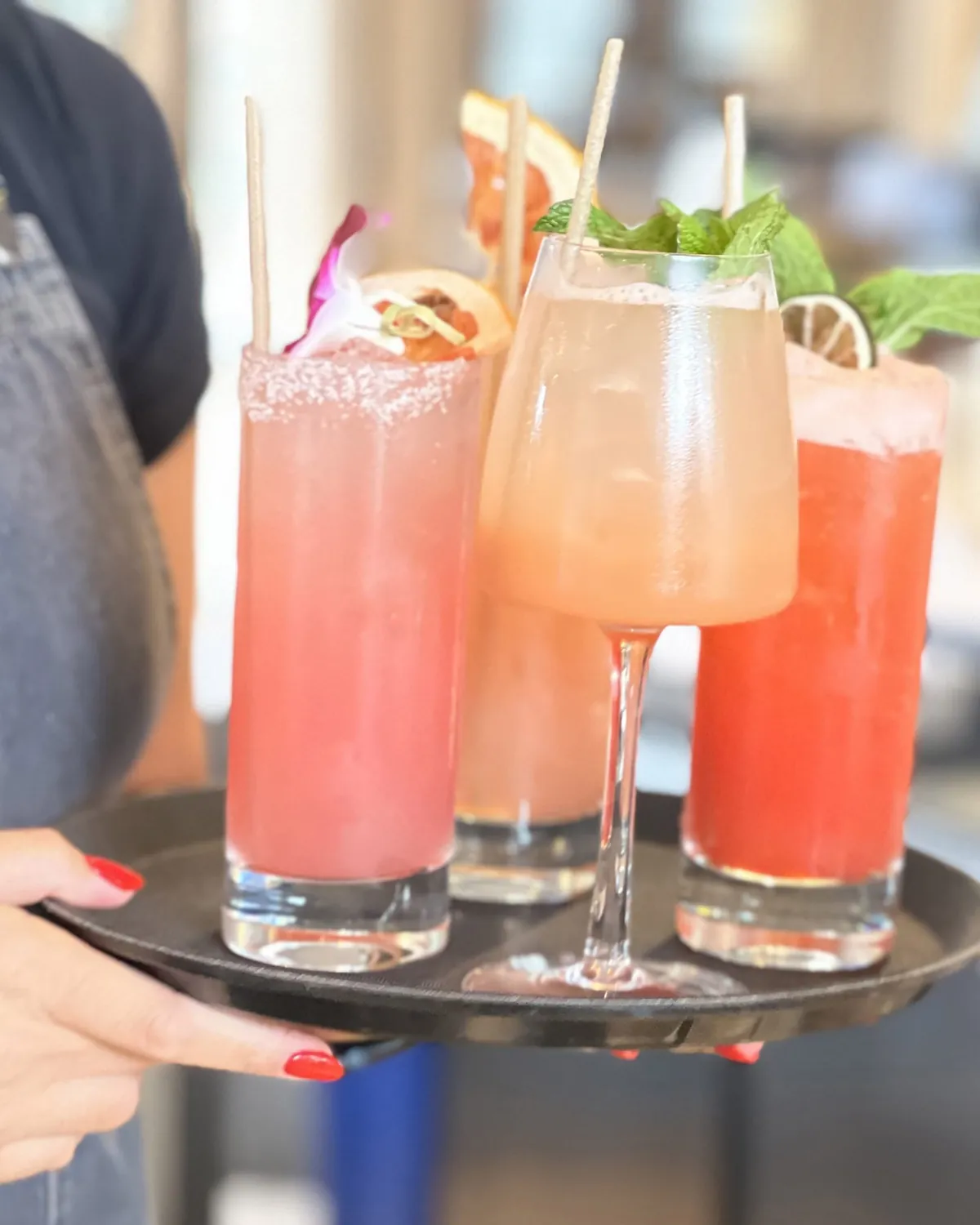 Vassoio servito in sala con tre cocktail alla frutta decorati con menta e agrumi