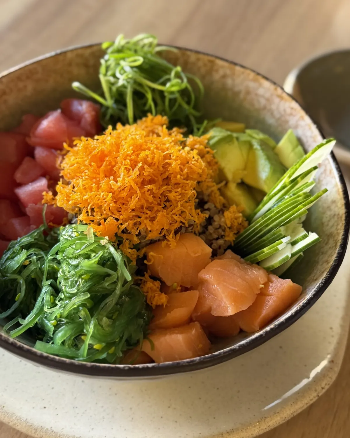 Poke di salmone e tonno con alghe wakame, avocado, cetriolo e carote in una ciotola di ceramica